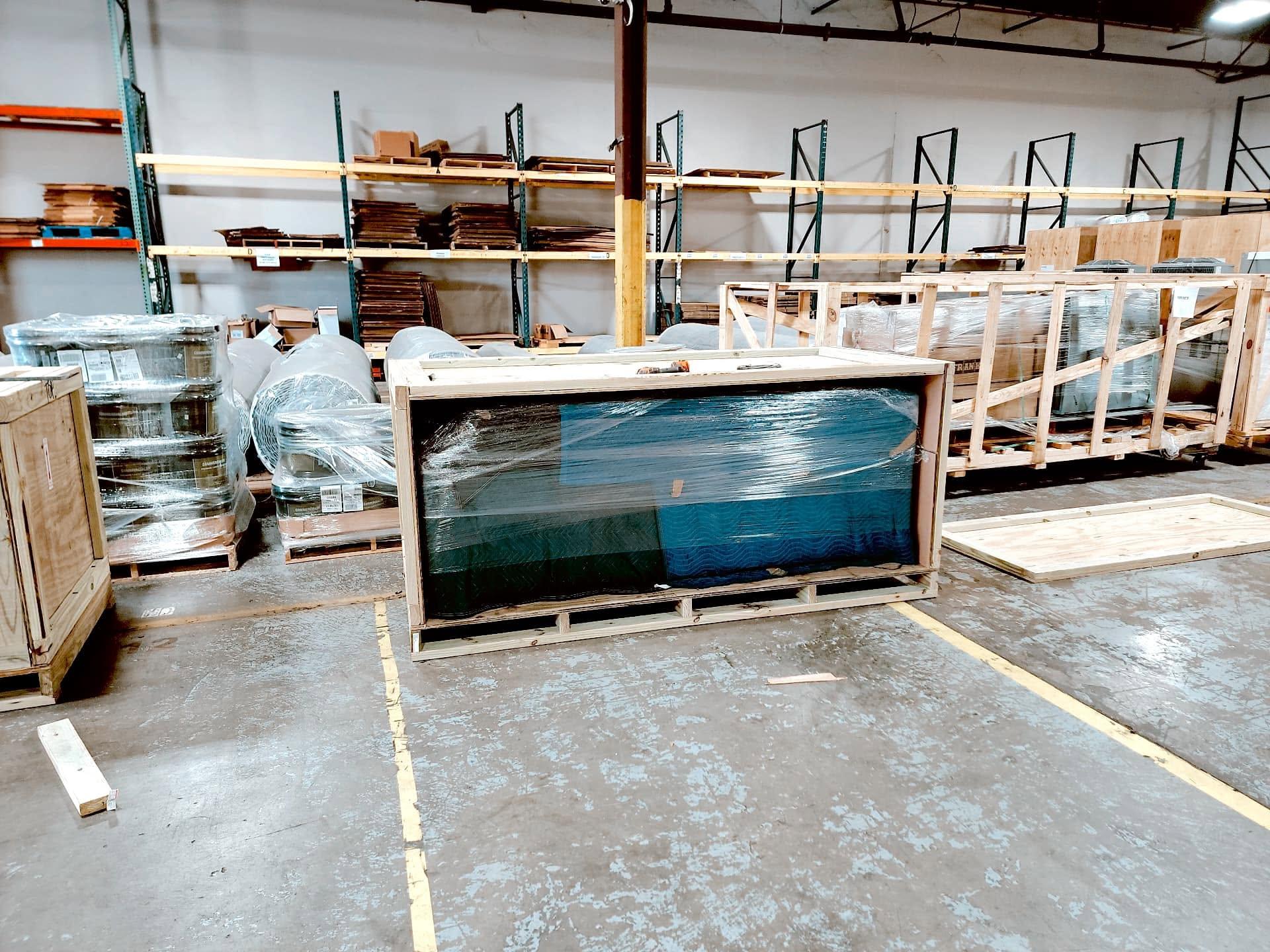 An open crate around a blanket-wrapped item in a warehouse